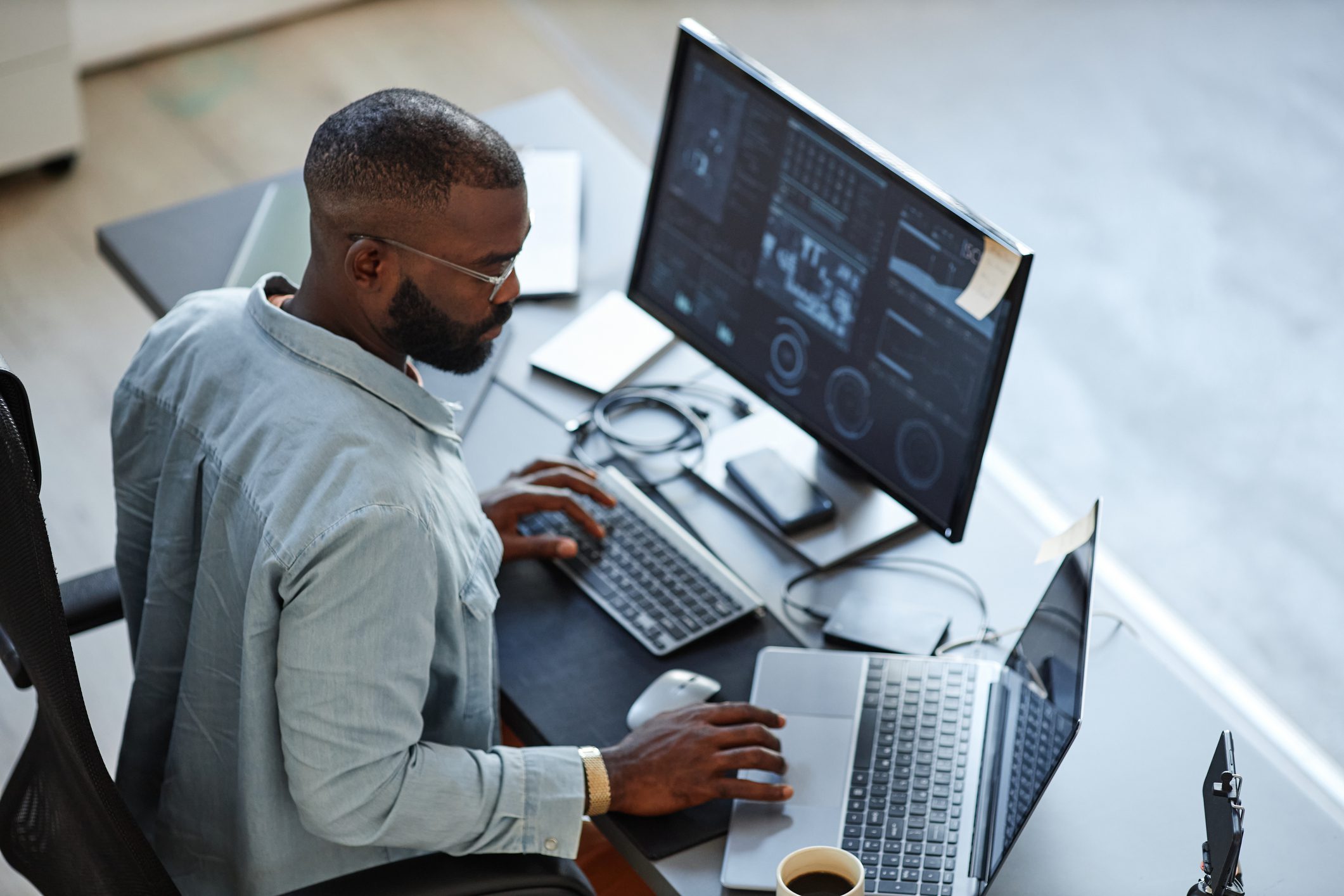 Man working on computer with multiple screens and a laptop.